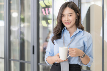 Young business woman drinking coffee in office. Woman hands holding hot cup of coffee or tea at co working space.