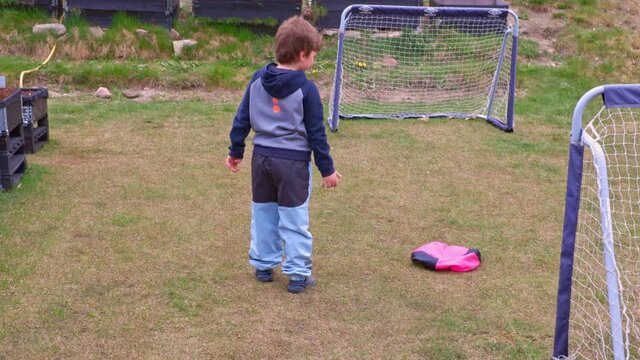Young boy throwing up parachute toy on backyard. Sweden.
