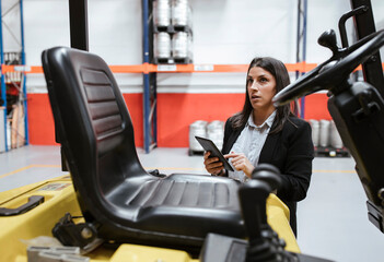 Confident female manager using digital tablet at illuminated warehouse
