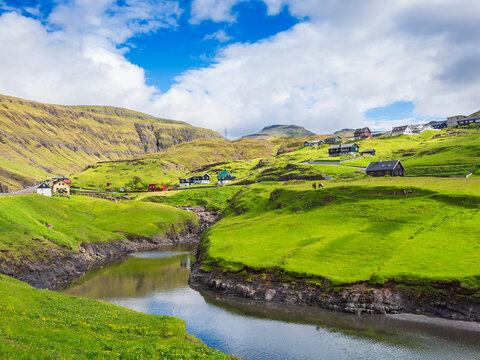 Houses over meadow in Leynar village against sky, Iceland