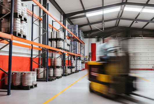 Male warehouse worker operating forklift at factory