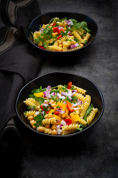 Studio shot of two bowls of&Ocirc;&oslash;&Omega;fusilli&Ocirc;&oslash;&Omega;pasta salad with chick-peas, bell peppers, arugula, Spanish onion, basil and parsley