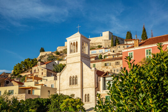 Croatia, Sibenik-Knin County, Sibenik, Church bell tower with Saint Johns Fortress in background