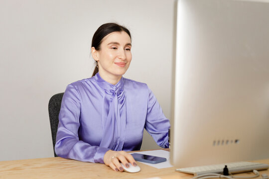Smiling female entrepreneur using computer while sitting at table in home office