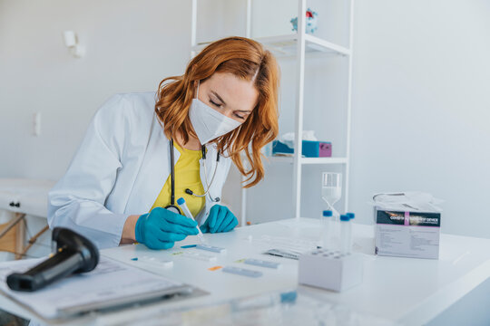 General practitioner testing sample on test cassettes while sitting at examination room