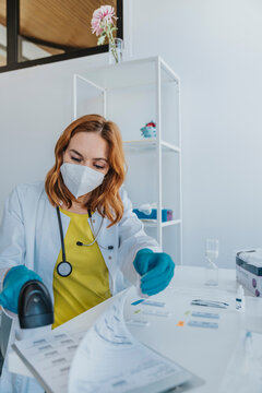 Female doctor using medical scanner on document while sitting at examination room