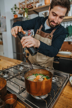 Expertise putting pepper on Broth soup while cooking in copper saucepan in kitchen