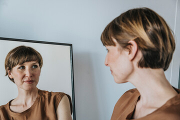 Thoughtful woman looking at reflection in mirror