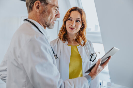 Coworker looking at doctor using digital tablet in clinic