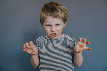 Angry boy gesturing while standing against gray background
