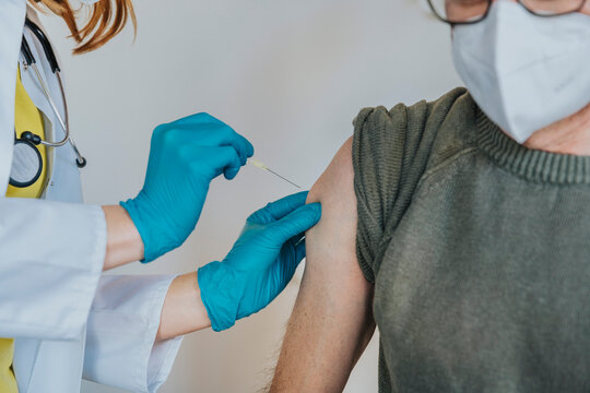 Doctor Giving COVID-19 Vaccine In Patient Arm At Examination Room