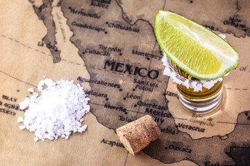glasses of golden tequila, served with salt and lemon, over vintage map of brazil