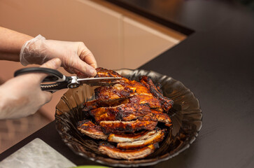 View of female cutting bbq pork ribs with kitchen sax. Sweden.