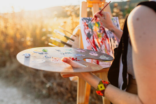 Young woman artist painting on easel