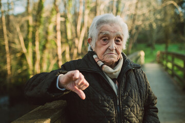 Displeased senior woman showing thumbs down gesture during winter