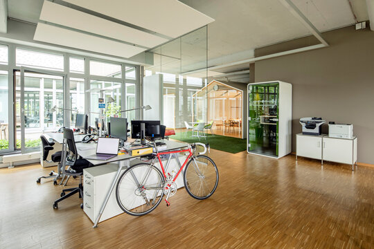 Bicycle, laptop and computers at desk in open plan office