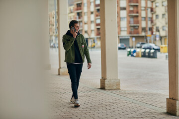Man in casual clothing talking on mobile phone while walking in arcade