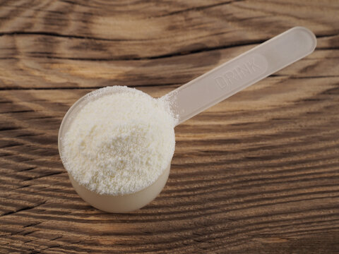 Protein powder, chondroitin, glucosamine in a plastic spoon for making a high-calorie drink on a wooden background, closeup, flat layout. Healthy sports nutrition for fitness