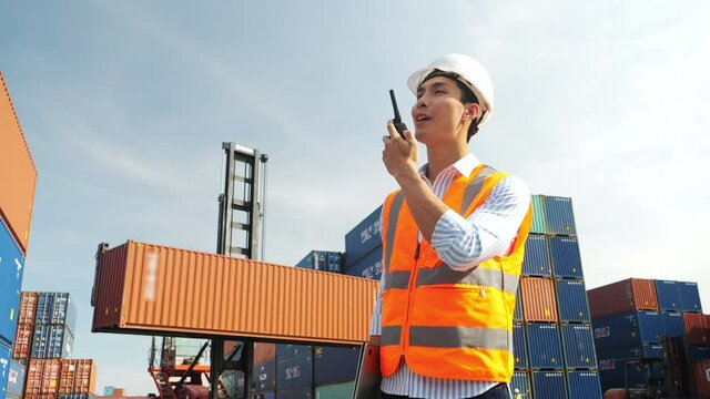 Front view of Mechanical engineer using walkie-talkie in Container cargo harbor. Business logistic commercial intermodal freight transport in import export, Cargo ship. shipping yard