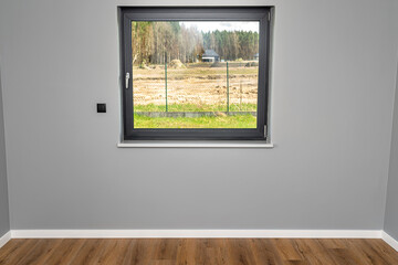 A large window in a room with gray walls and fully open roller shutters.