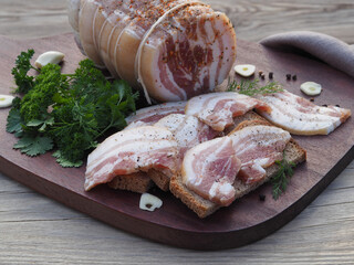 Salted lard with bacon, marinated in spices, slices with rye bread, garlic, fresh herbs on a...