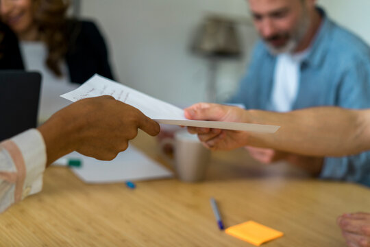 Coworkers giving document to each other at during meeting in office