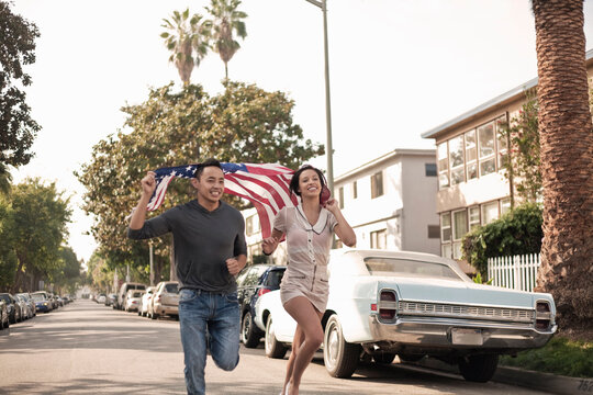 Young male and female running with American flag on street