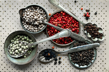Different types of pepper in spoons, white pepper, red pepper, Szechuan pepper, green pepper, black pepper