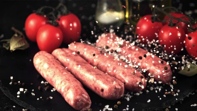 Super slow motion on the raw sausage drops salt and pepper. Filmed at 1000 fps.On a black background.