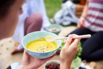 Woman with food bowl sitting by friends