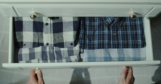 Man opens drawer with shirts