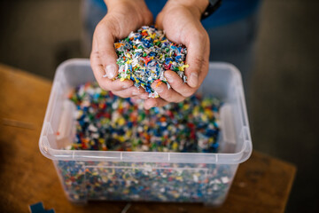 Man with container holding recycled plastic in factory