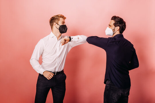 Entrepreneurs giving elbow bumps while greeting against colored background
