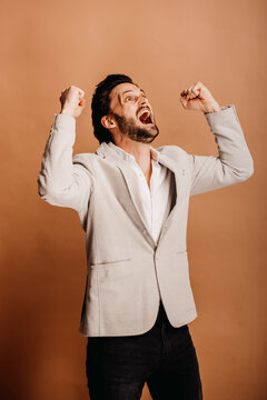 Screaming businessman with arms raised looking away against brown background
