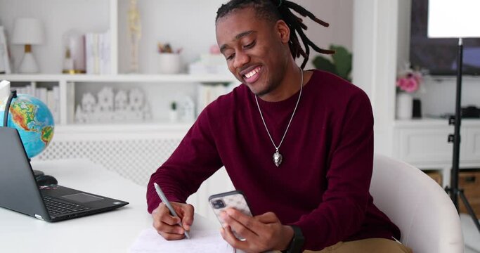 Portrait Of Young African American Man Writing Notes While Sitting At The Desk At Home