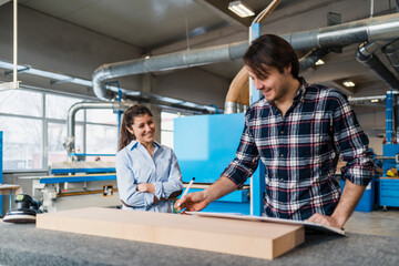 Manual worker measuring wood while standing by colleague at industry