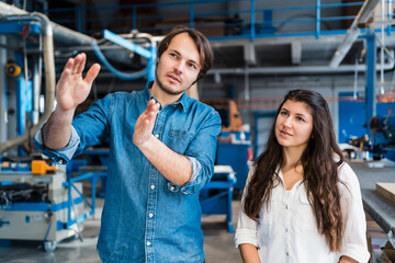 Male expertise explaining colleague while standing with colleague at industry
