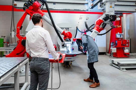 Men examining at robotics in factory