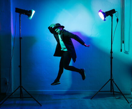 Man in casual clothing dancing against colored background