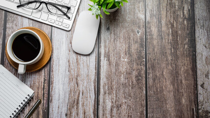 top view of wooden desk with keyboard coffee cup glasses. Copy space.