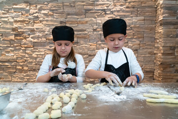 Fototapeta na wymiar Boy and girl cooking a pastry dressed as professional chefs