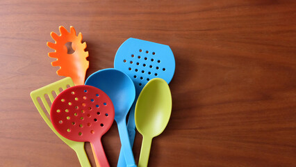 A variety of colorful kitchen utensils on a wooden surface.