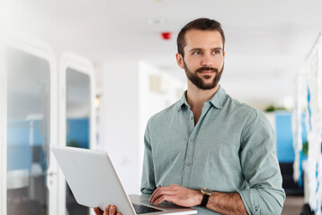 Young male professional with laptop standing at office
