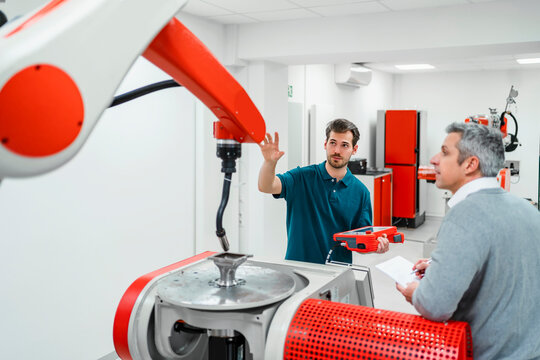 Male engineers discussing over machinery in industry