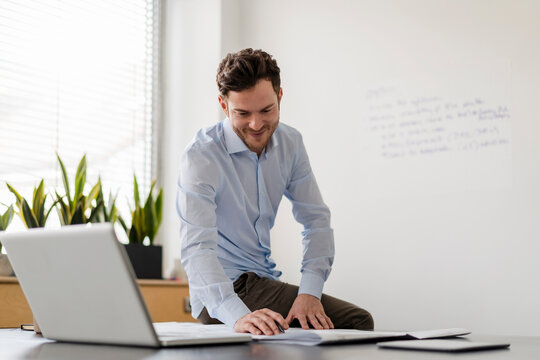 Smiling male entrepreneur examining blueprint at office
