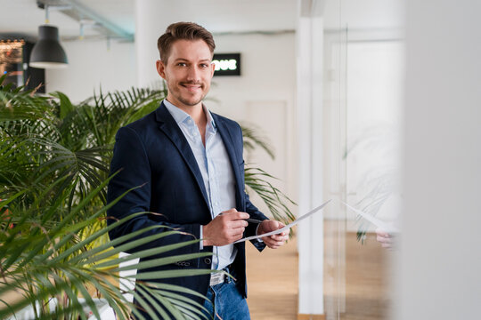 Confident businessman with document standing in office
