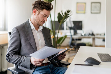 Male entrepreneur working on document and digital tablet at office