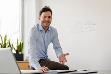 Smiling businessman with document at desk in office