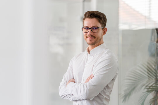Confident male entrepreneur with arms in office