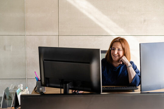 Smiling businesswoman working on computer while sitting at desk in cabin